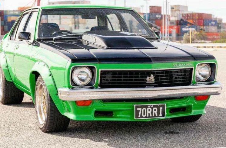 Lime green Holden Torana sedan with black bonnet and scoop, wide wheel flares and gold wheels