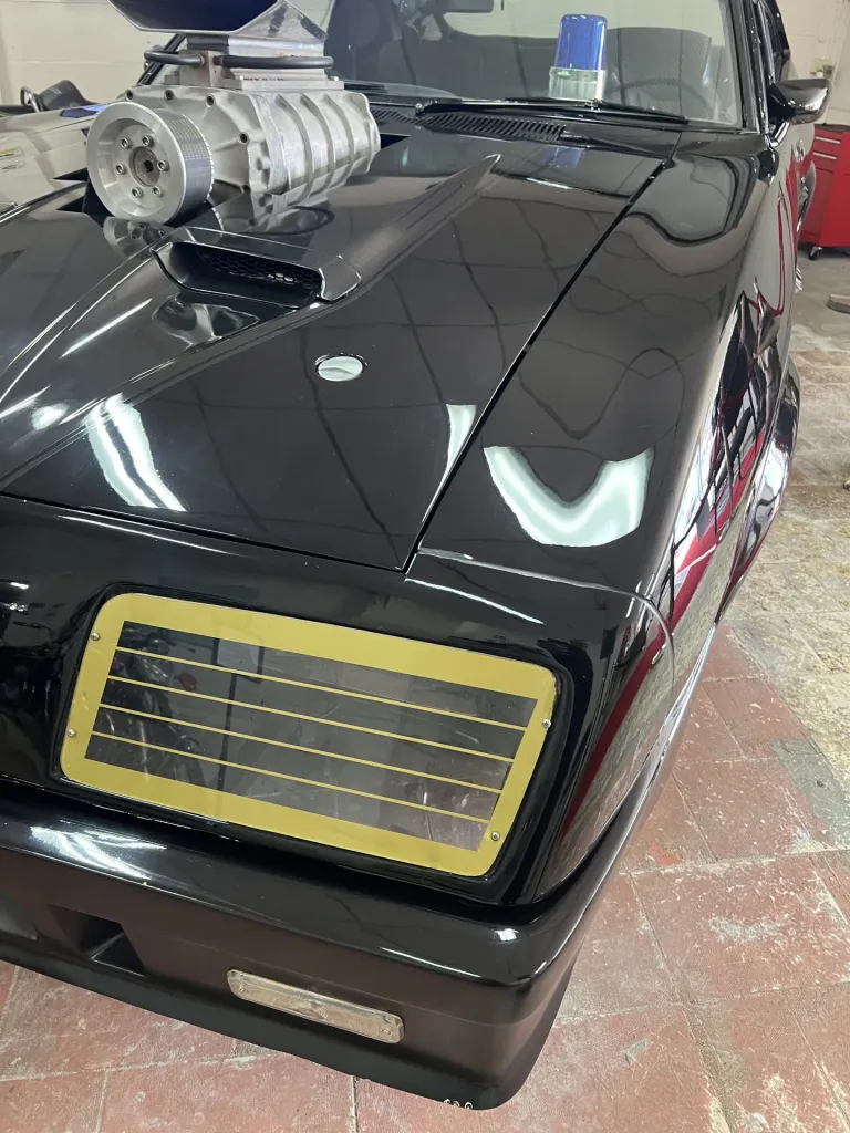 Close-up of the black Interceptor replica's bonnet supercharger and gold headlight grille