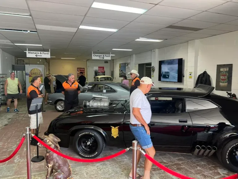Visitors and staff in the museum showroom around a black Interceptor replica with supercharger